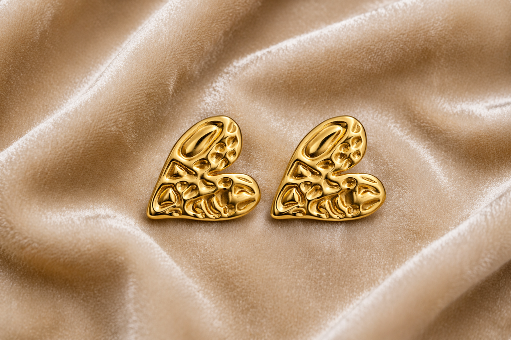 Gold heart shaped stud earrings on velvet