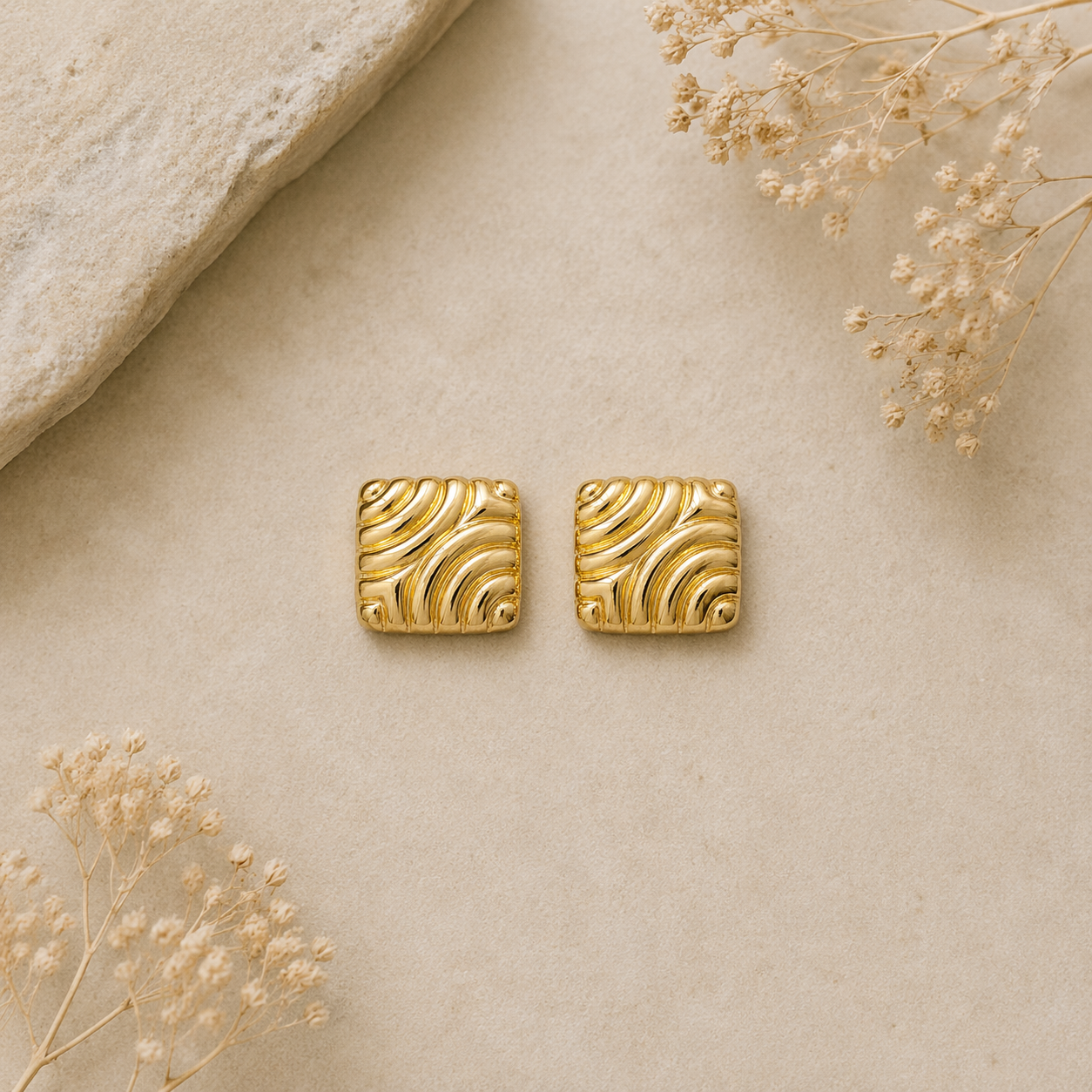 Square gold stud earrings on marble