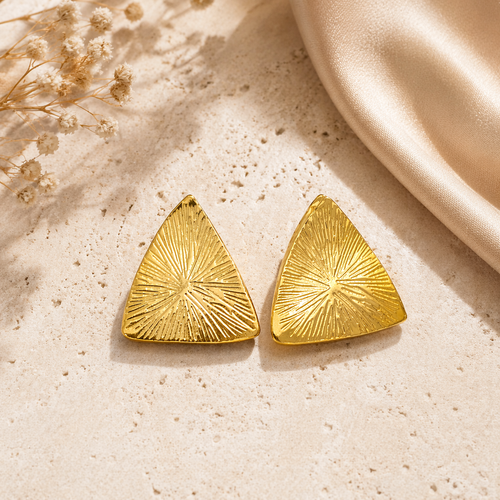 Bold gold stud earrings on marble