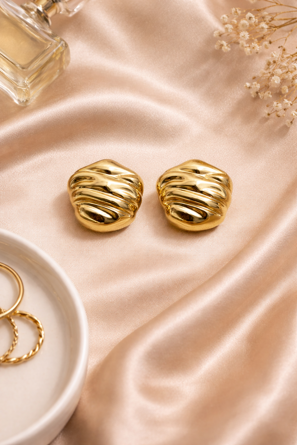 Bold gold stud earrings on satin