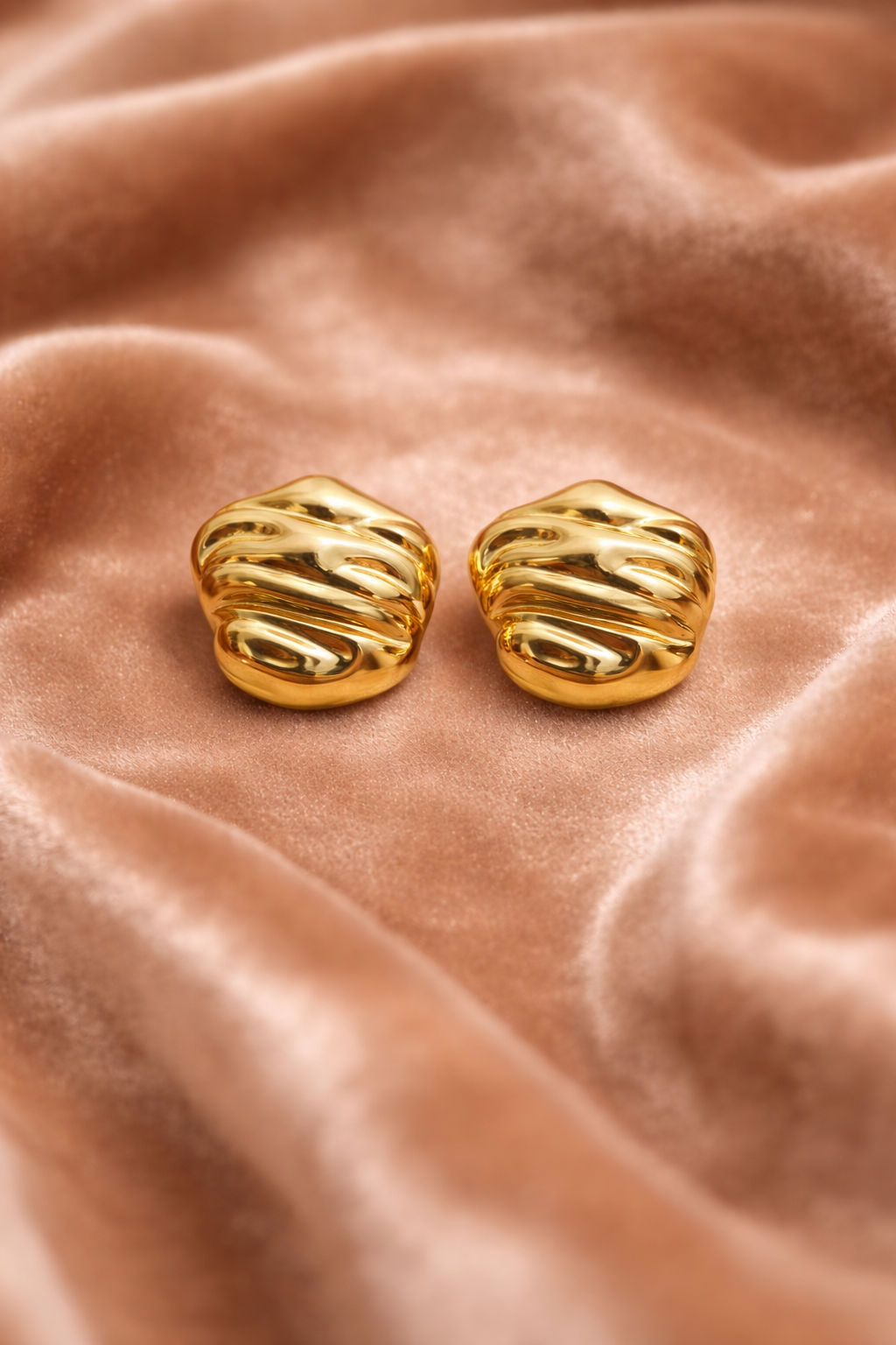 Bold gold stud earrings on velvet