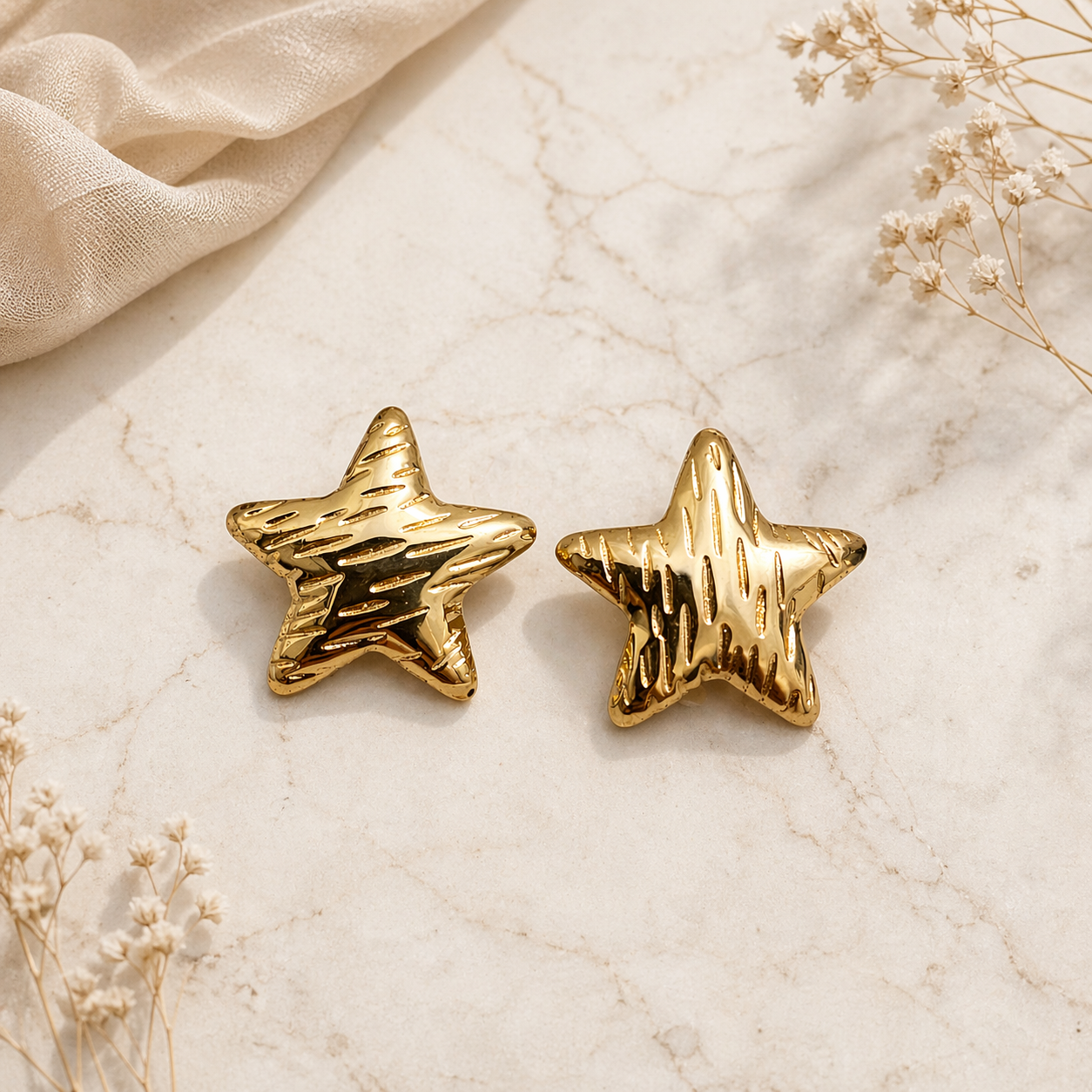 Textured gold star stud earrings on marble 