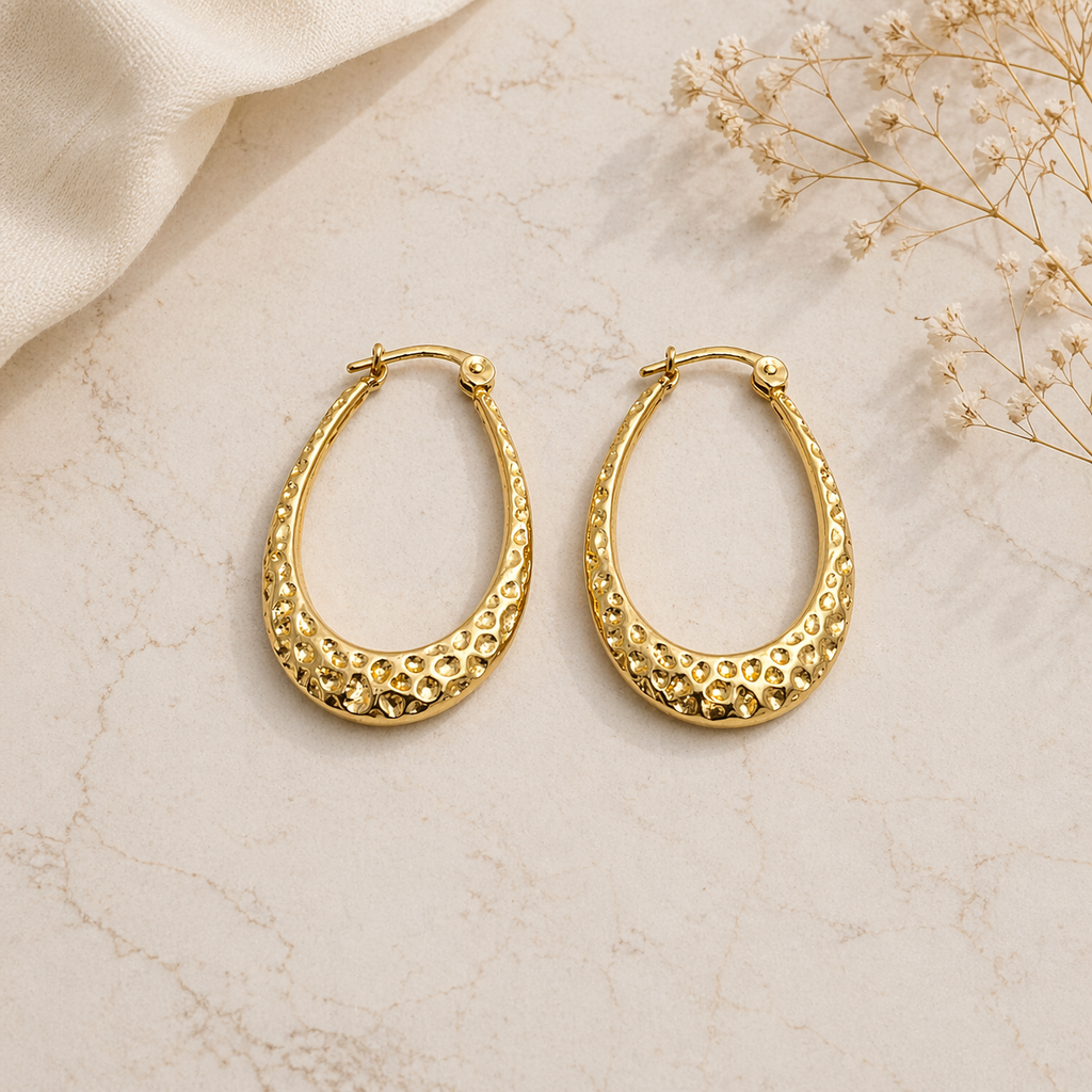 Textured gold hoop earrings on marble 