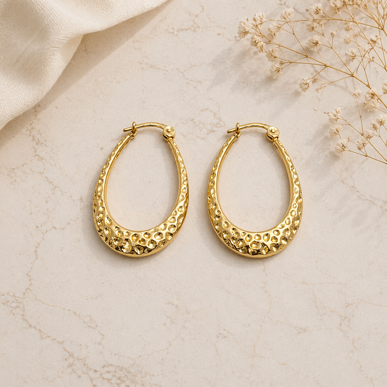 Textured gold hoop earrings on marble 