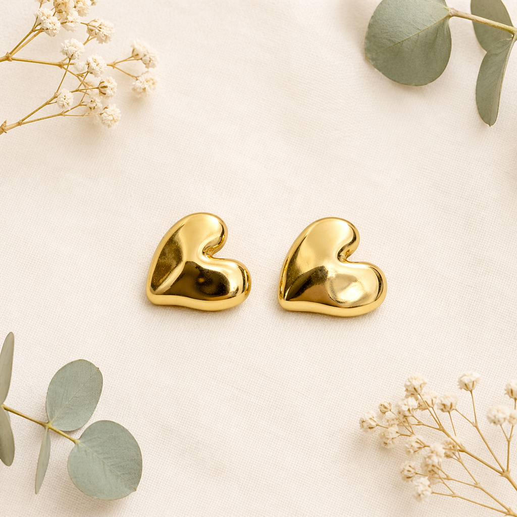 Sleek gold heart stud earrings on marble