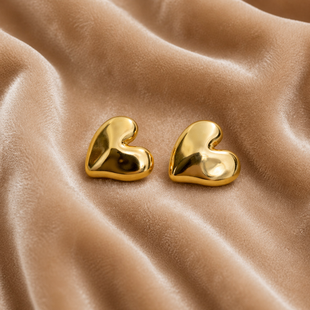 Sleek gold heart stud earrings on velvet
