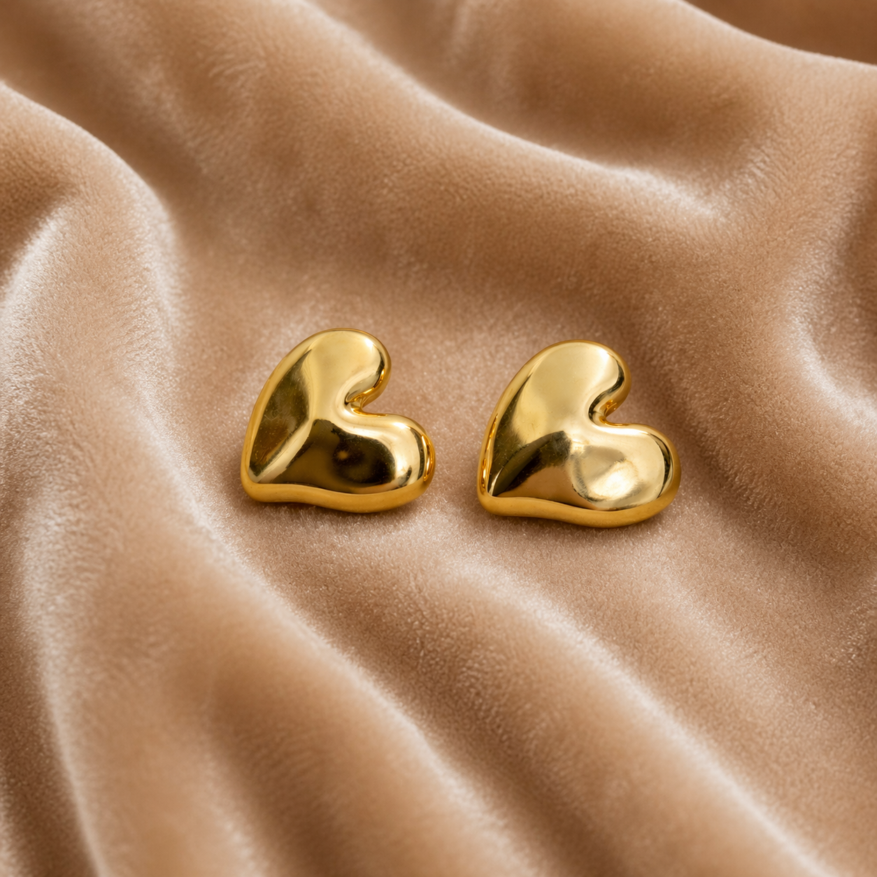 Sleek gold heart stud earrings on velvet