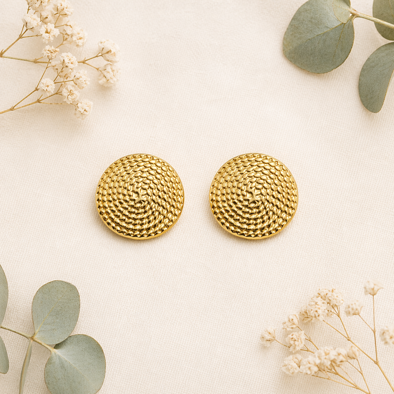 Round textured gold stud earrings on marble 