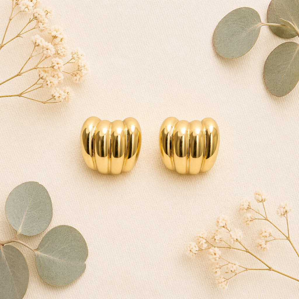 Gold ribbed stud earrings on flat