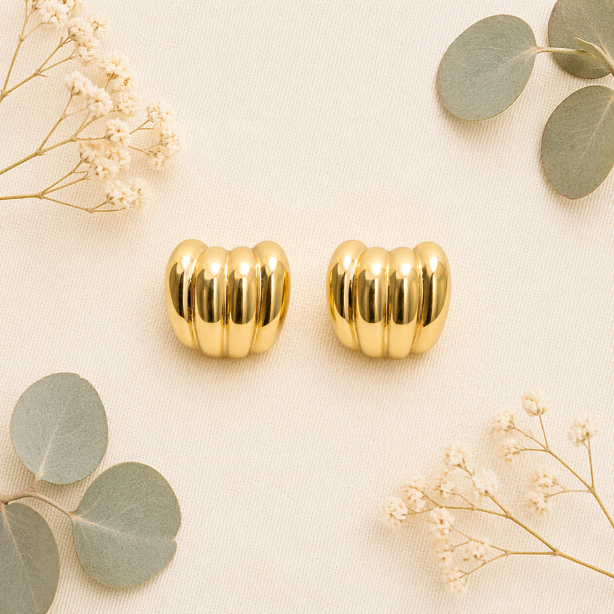 Gold ribbed stud earrings on flat