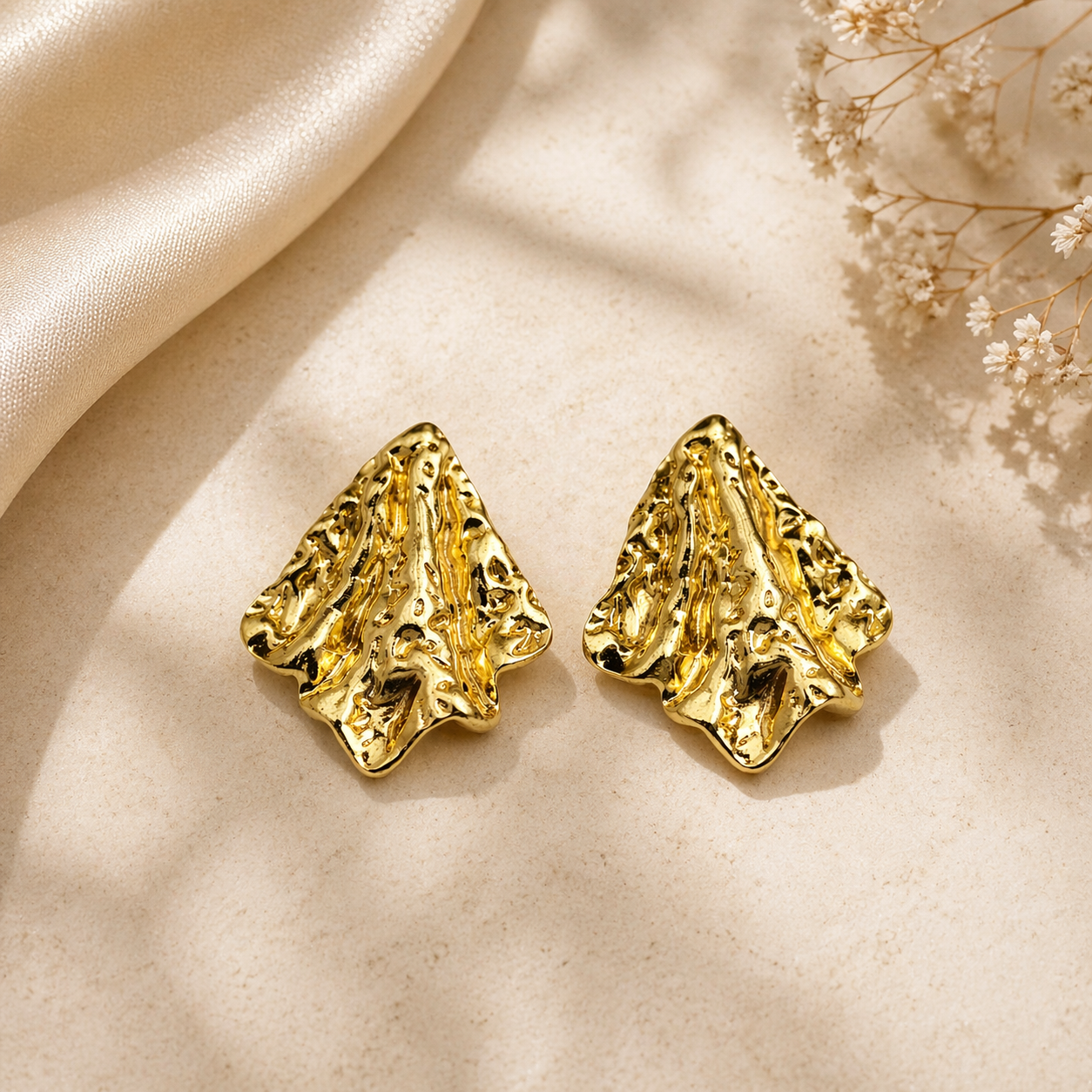 Elegant gold textured stud earrings  on marble