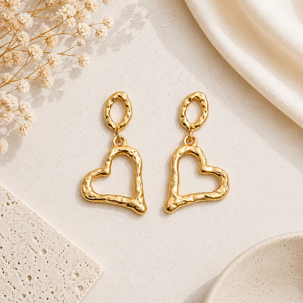 Gold heart drop earrings on marble 