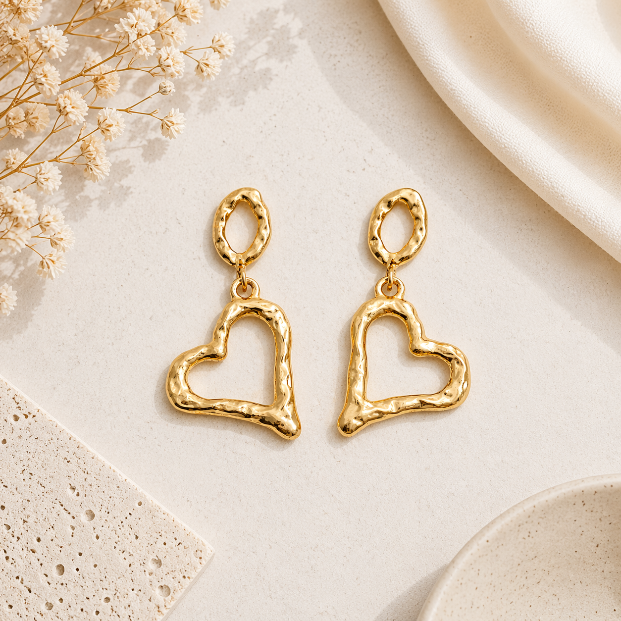 Gold heart drop earrings on marble 