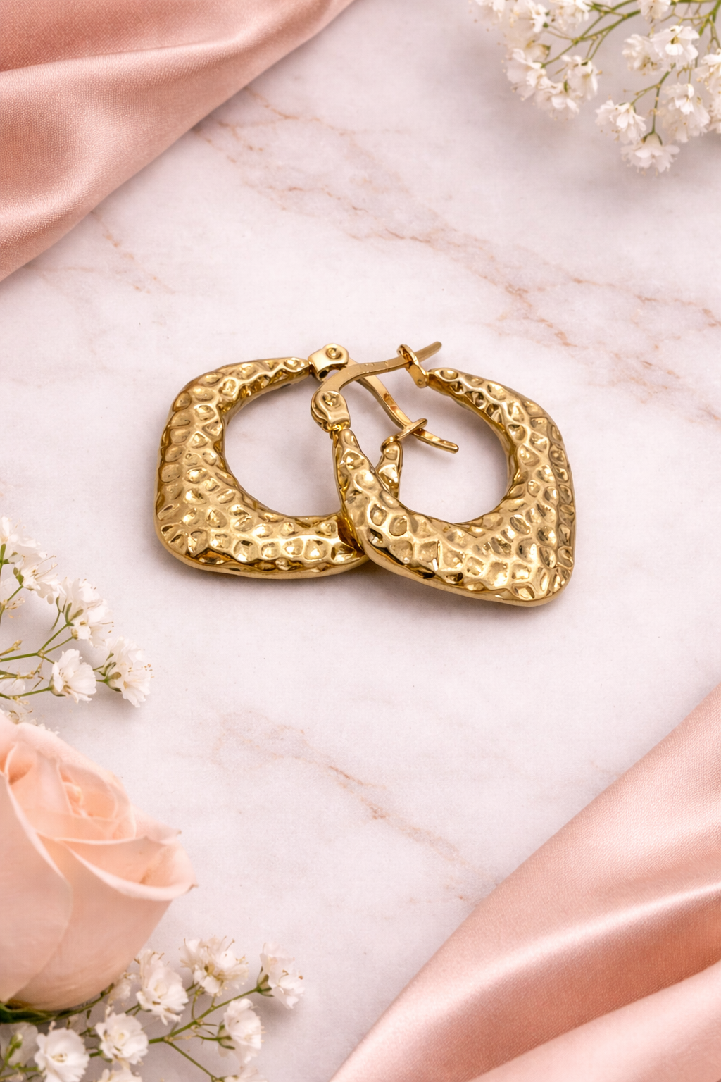 Textured gold hoop earrings on marble 