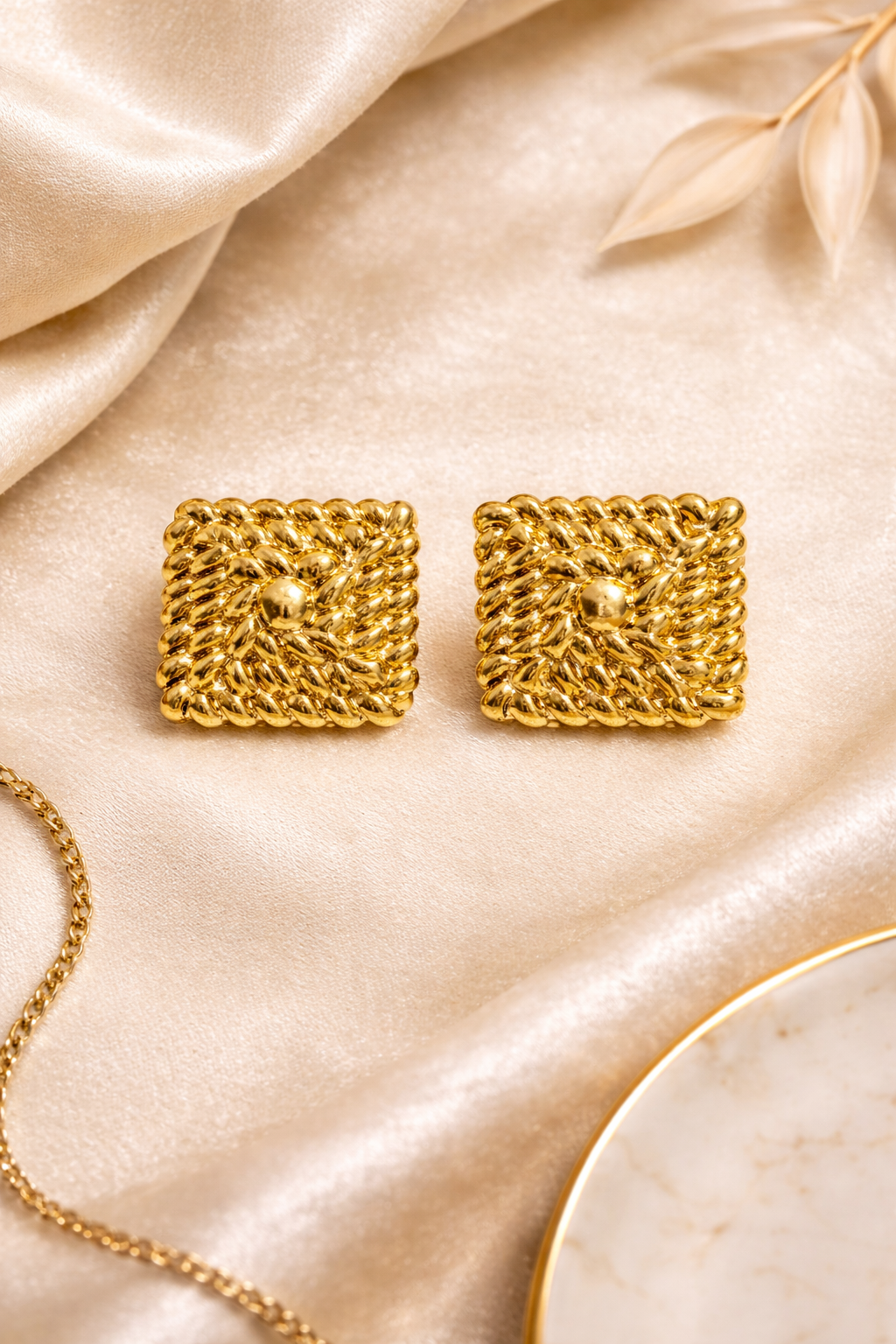 Gold square stud earrings on flat surface