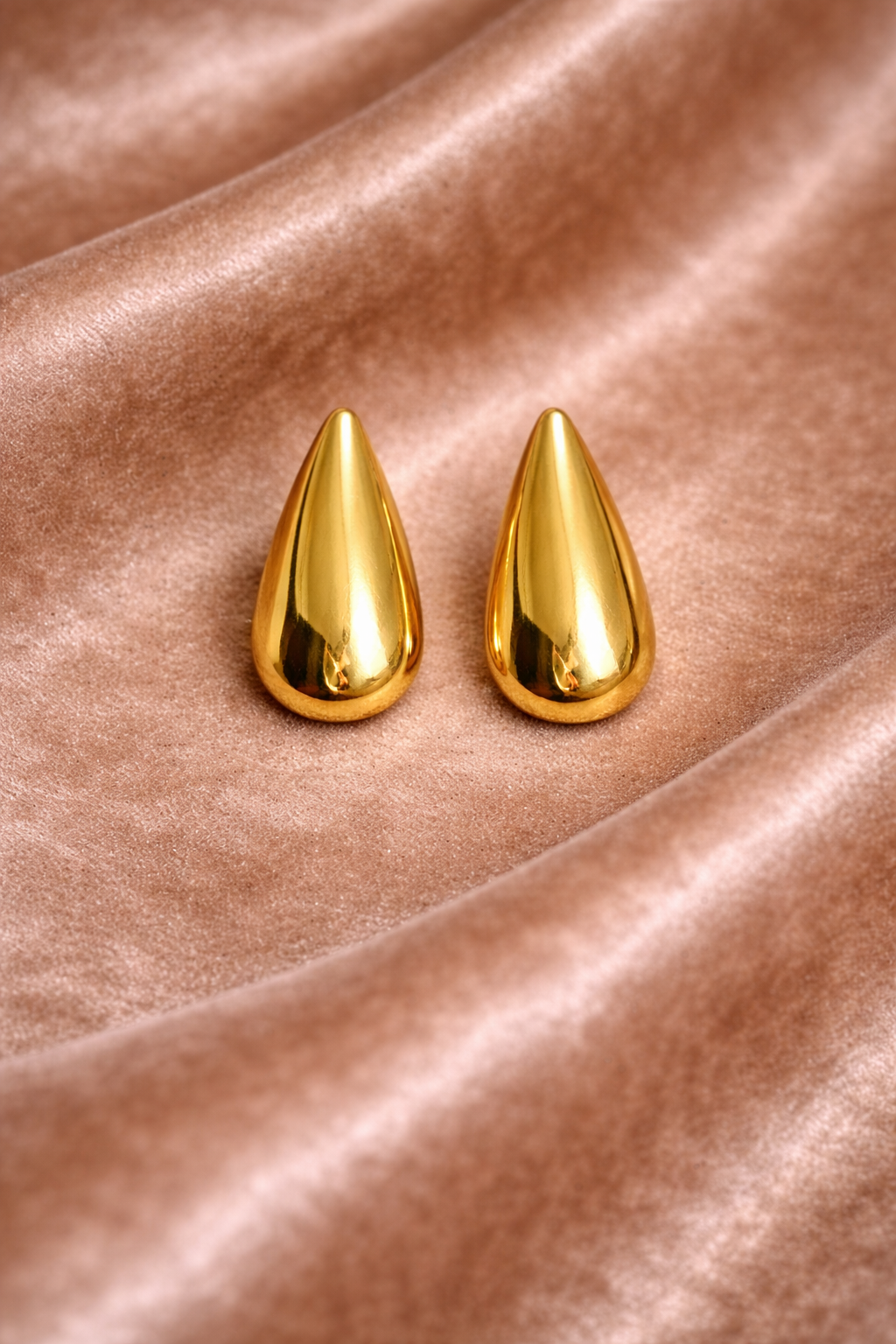 Elegant gold teardrop earrings on velvet