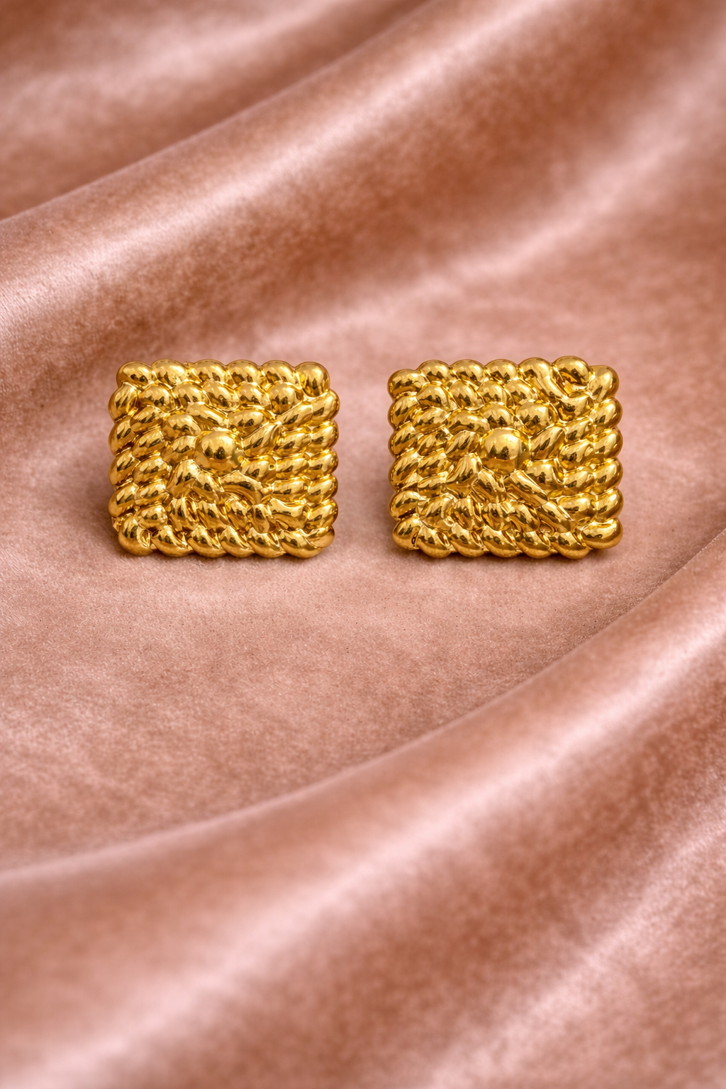Gold square stud earrings on velvet