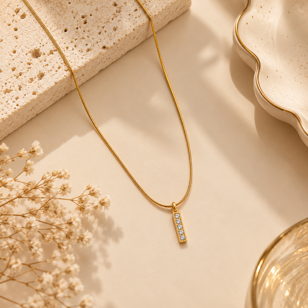 Gold Bar Pendant Necklace with Crystal Accents on flat lay 