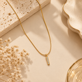 Gold Bar Pendant Necklace with Crystal Accents on flat lay 